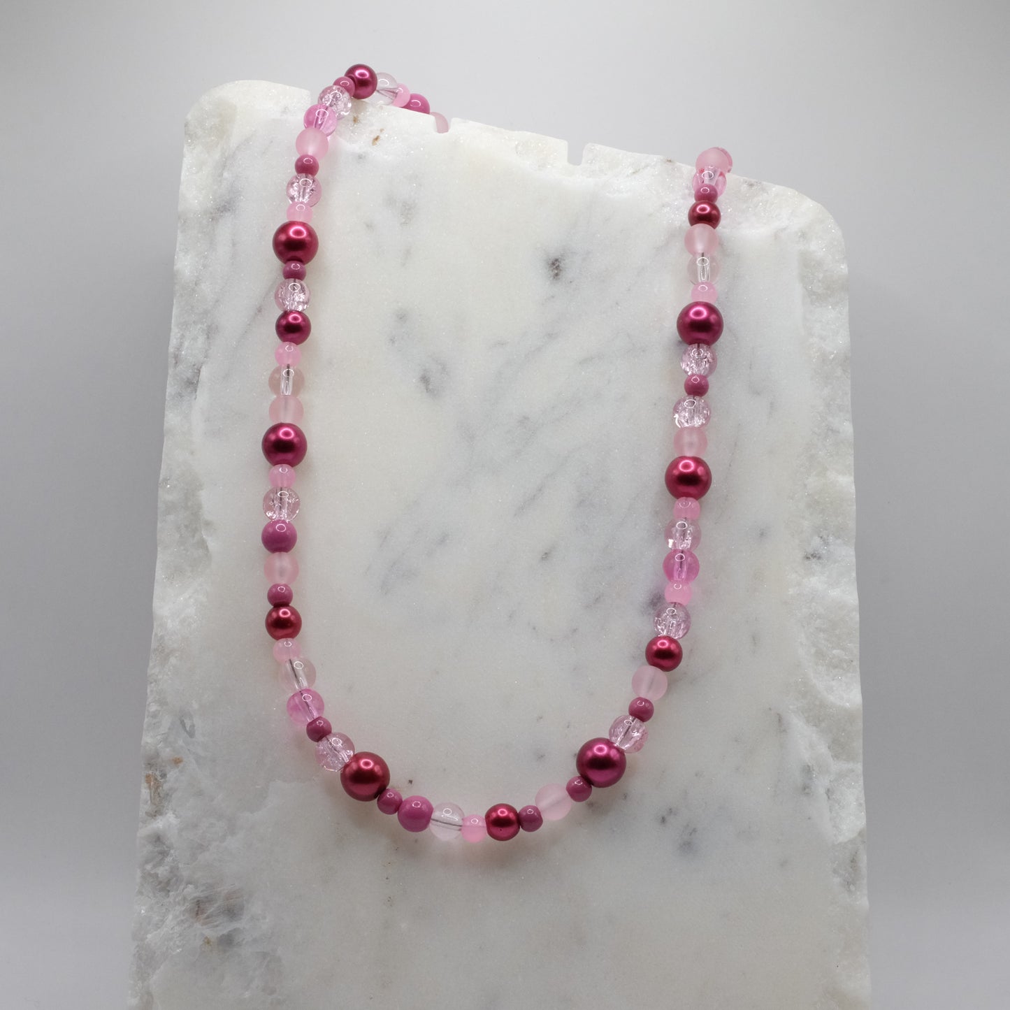 Pink beaded necklace on a marble surface