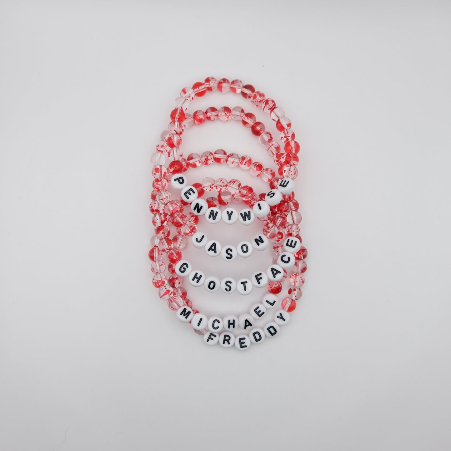 Set of beaded bracelets with letter beads spelling out names on a light gray background