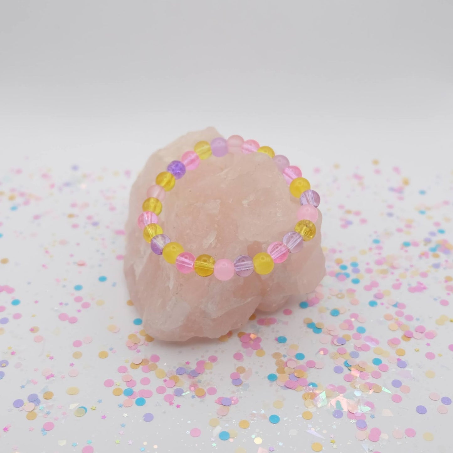 Pink, purple and yellow beaded necklace on a white background with confetti