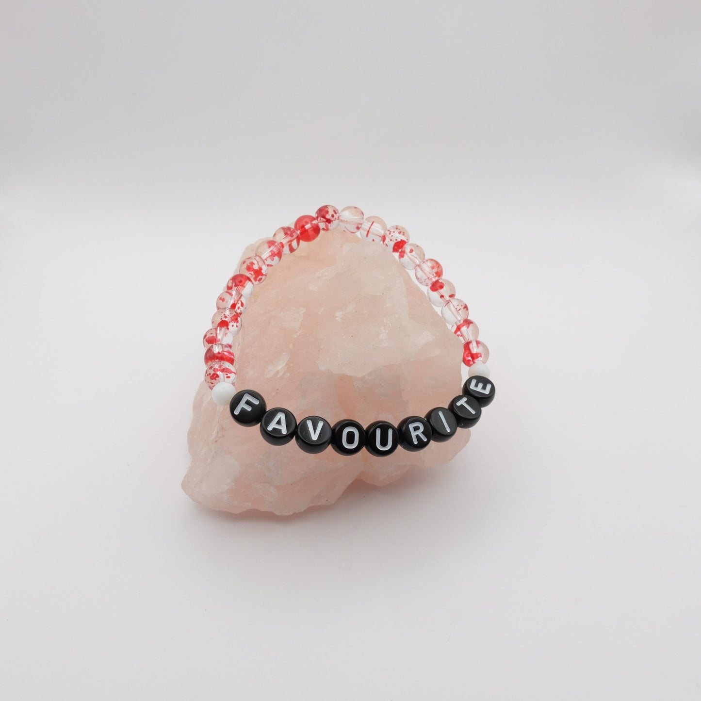 Bracelet with red beads and 'FAVOURITE' beads on a pink stone