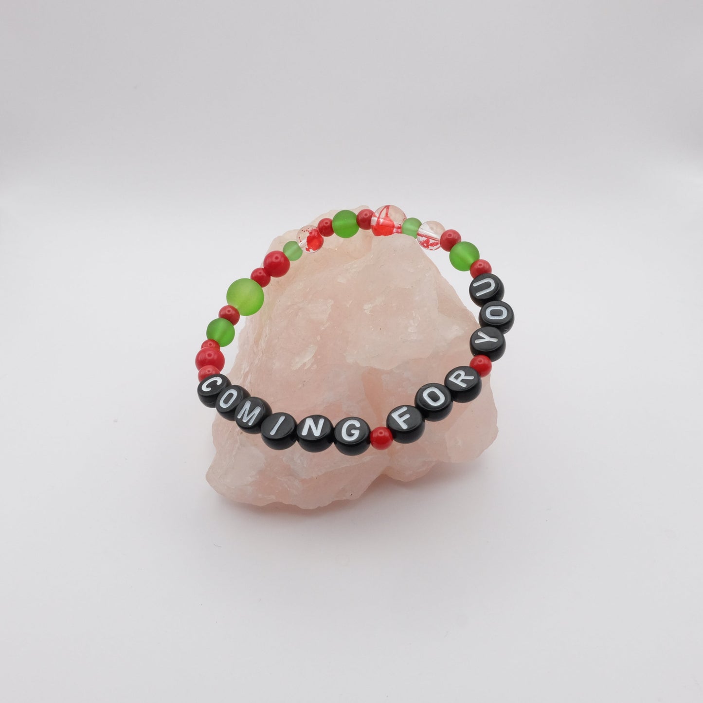 Green and red beaded bracelet with 'COMING FOR YOU' message on a white background