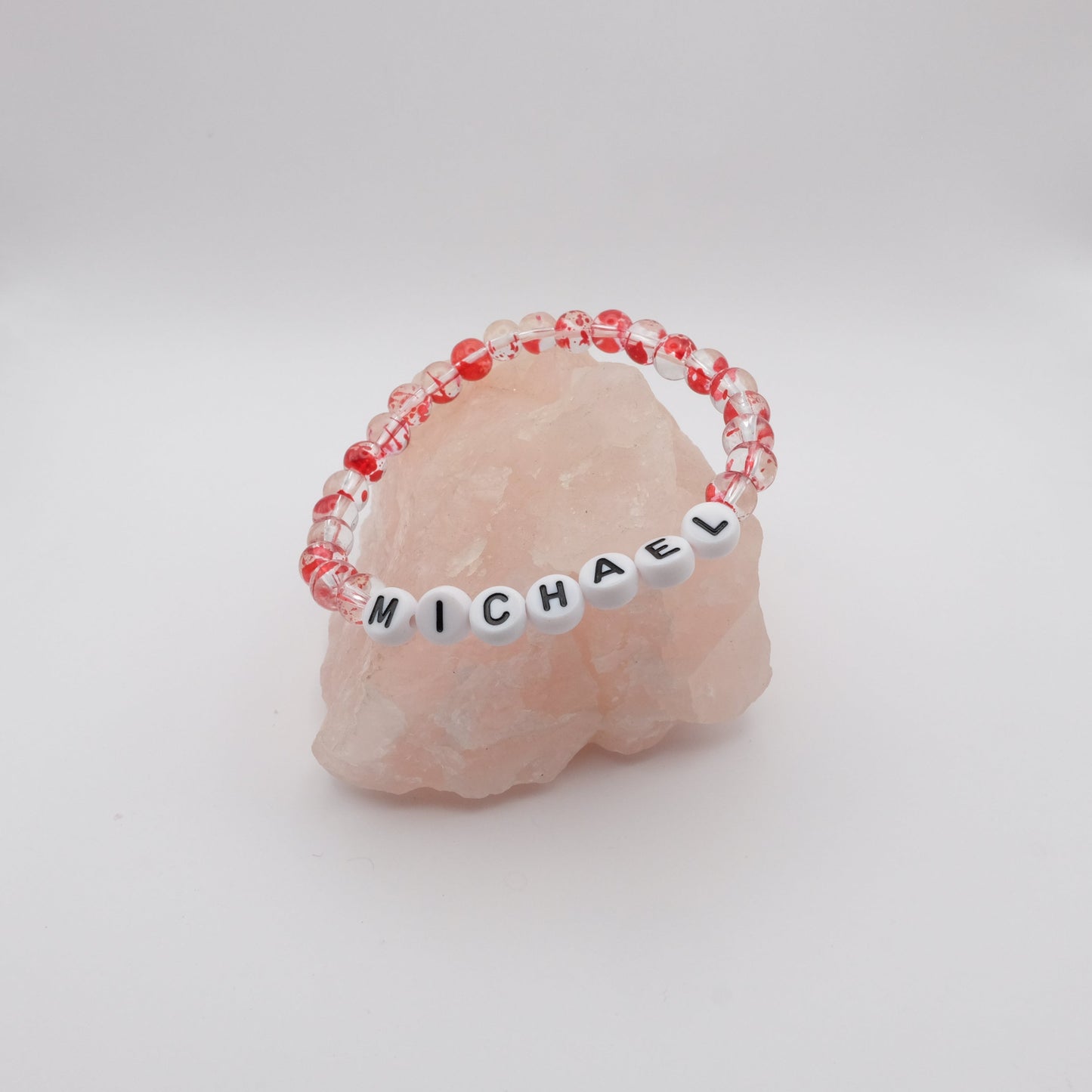 Bracelet with 'MICHAEL' beads on a pink stone with a white background
