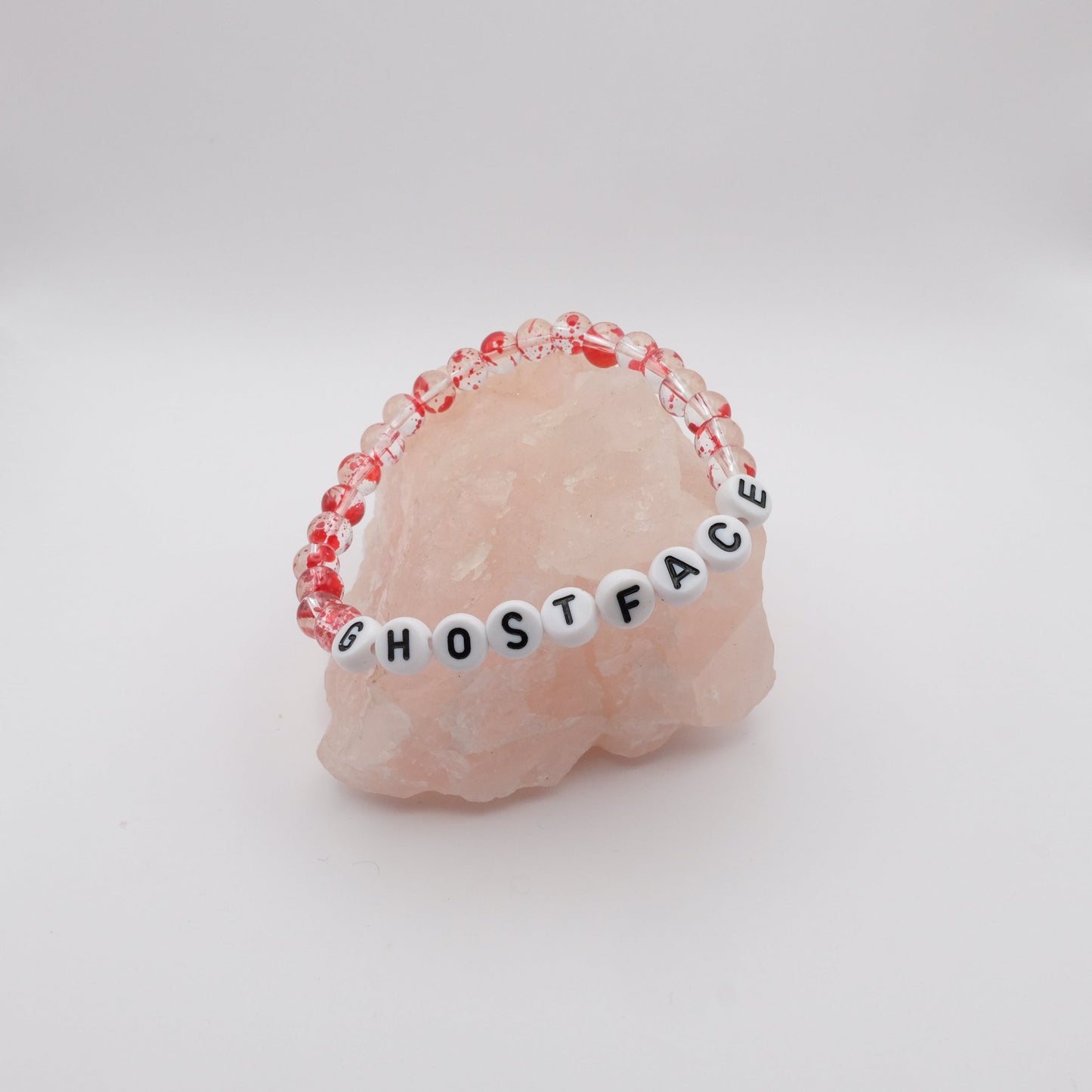 Bracelet with 'GHOSTFACE' beads on a pink stone background