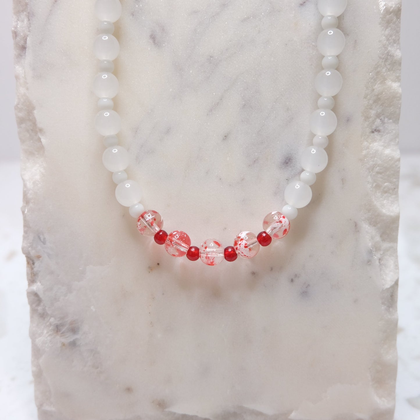 Necklace with red and white beads on a textured surface