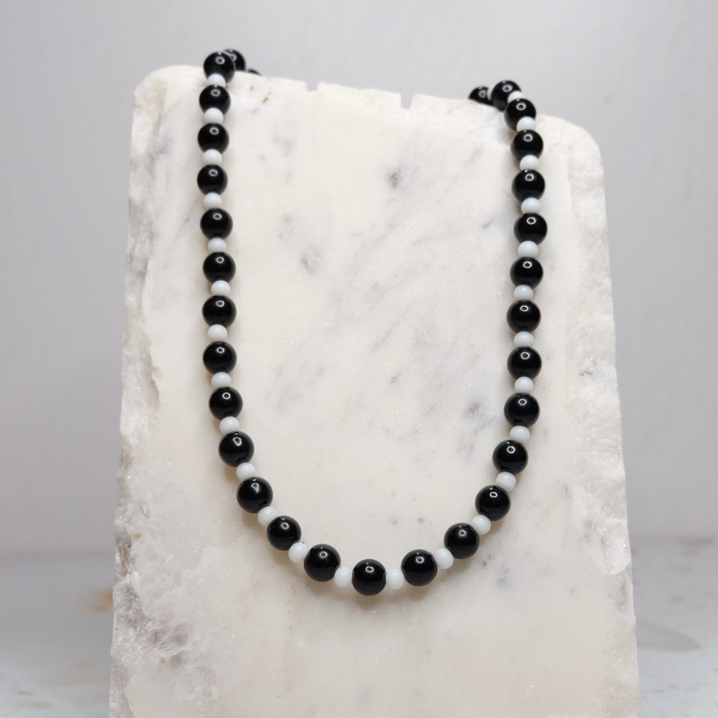 Black beaded necklace on a white marble surface