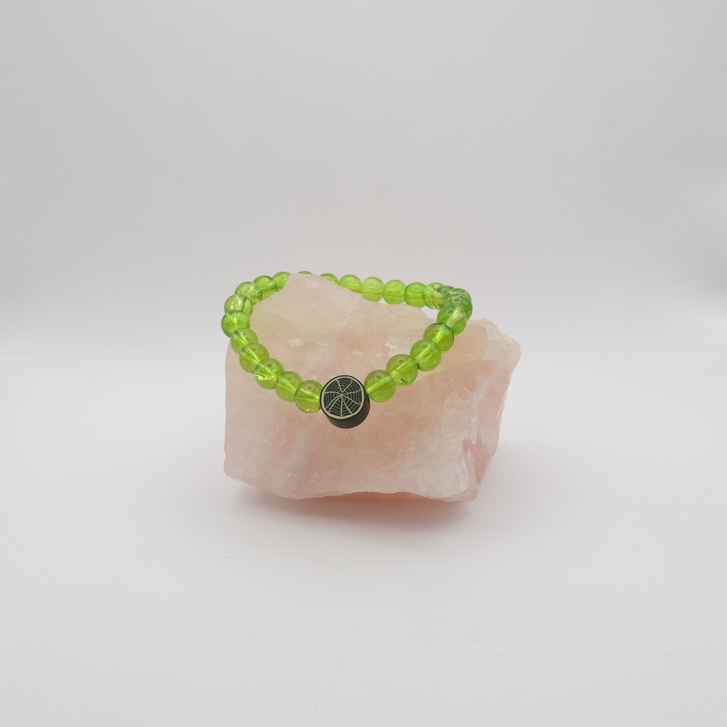 Green beaded bracelet with a black spiderweb bead on a white stone
