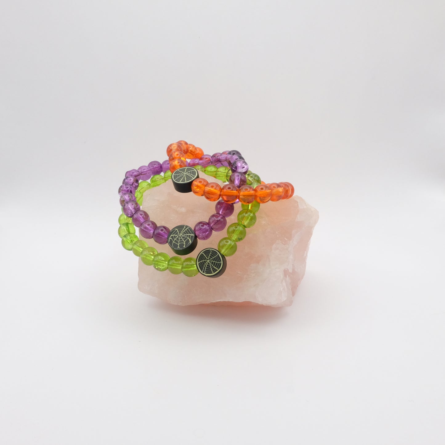 Set of colorful beaded bracelets on a piece of pink stone with a white background