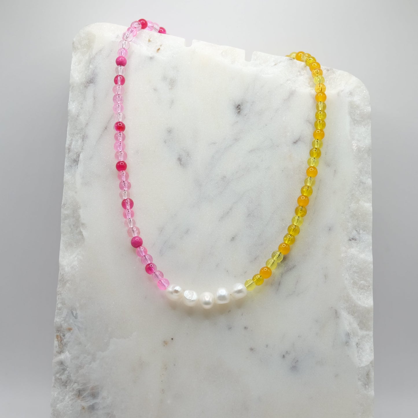 Necklace with pink and yellow beads on a marble surface