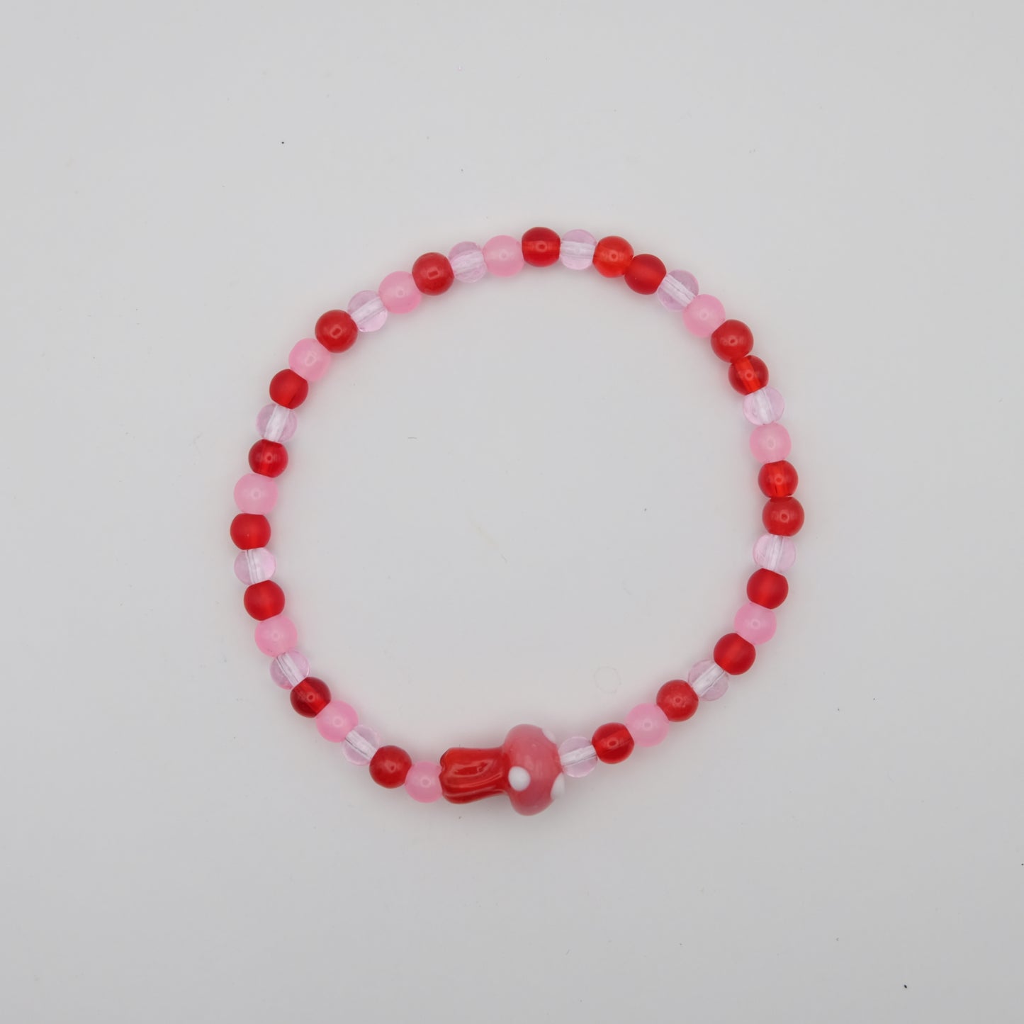 Beaded bracelet with red and pink beads on a light gray background