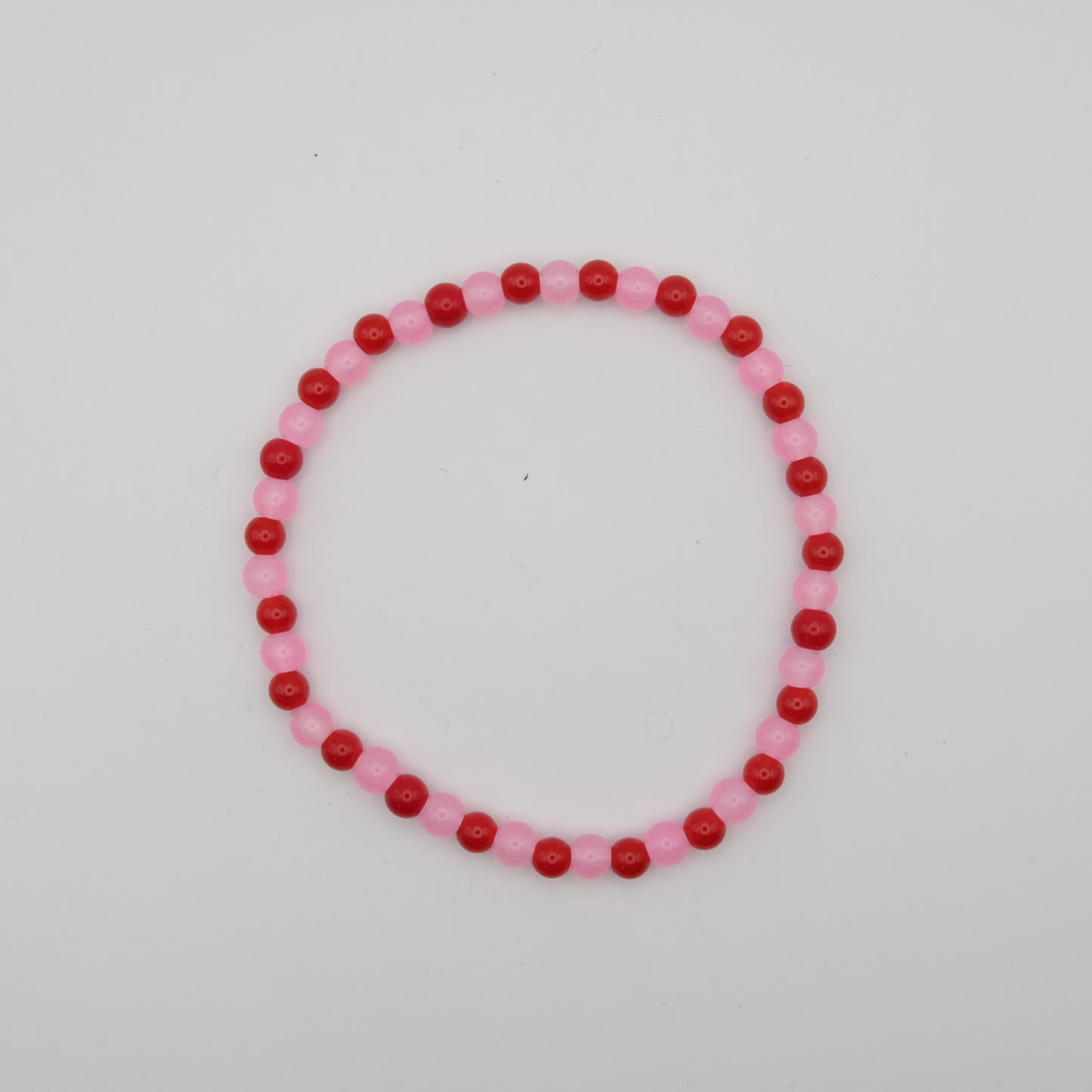 Beaded bracelet with pink and red beads on a white background
