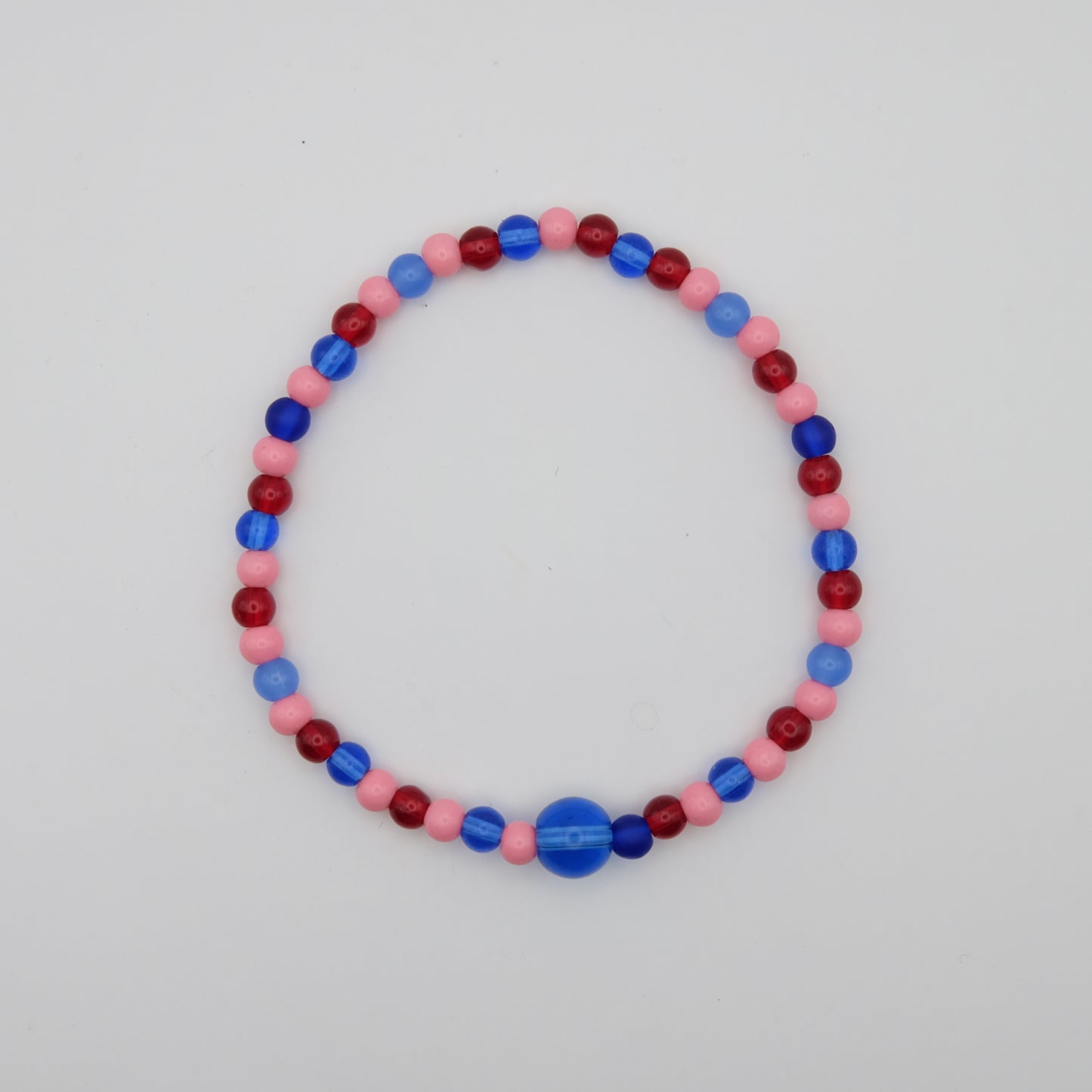 Beaded bracelet with red, blue, and pink beads on a light gray background