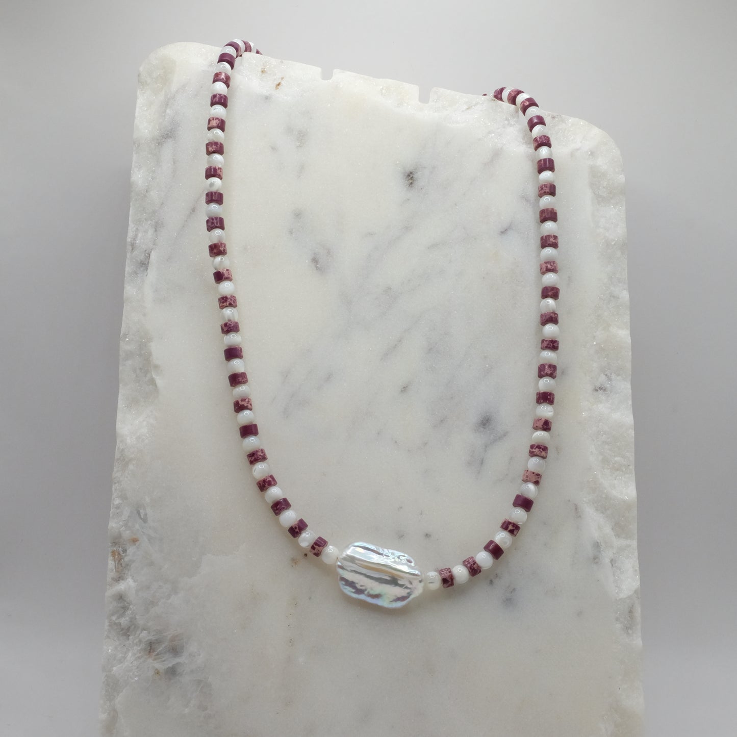 Necklace with red and white beads on a marble surface