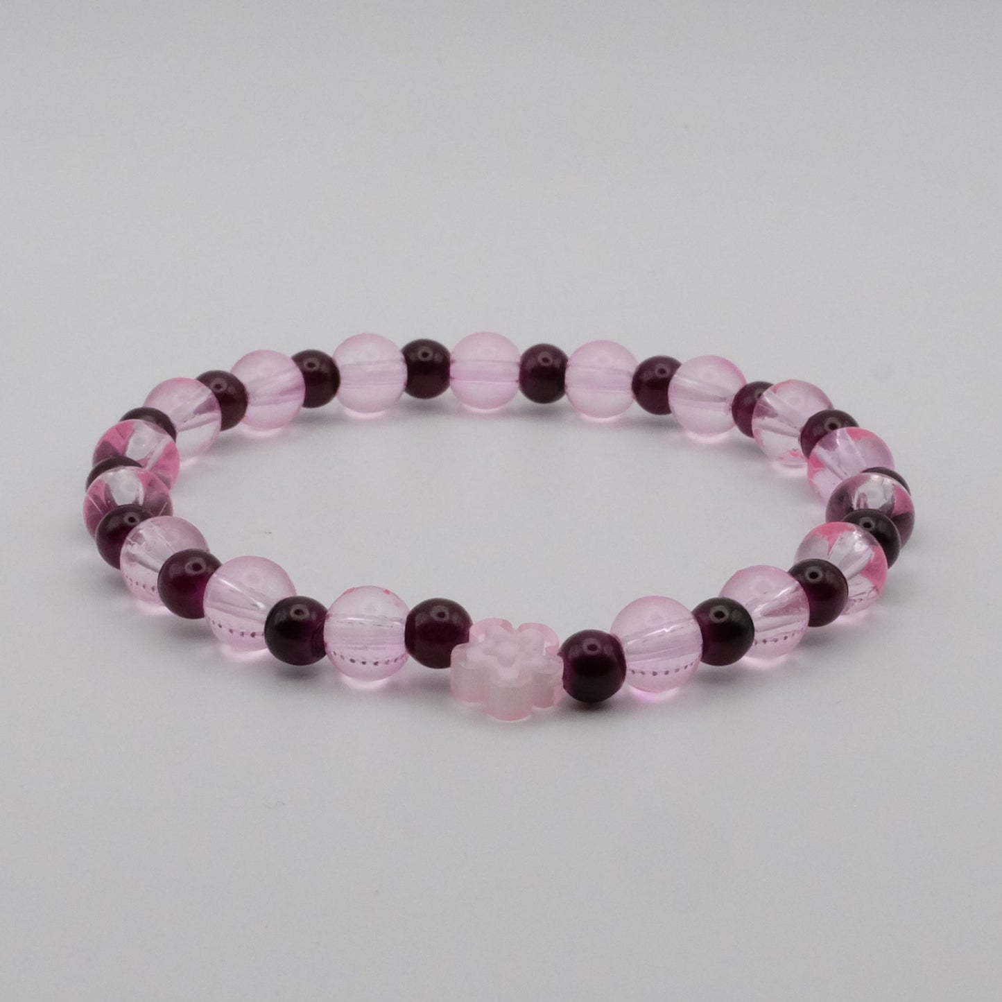 Beaded bracelet with pink and purple beads on a light gray background