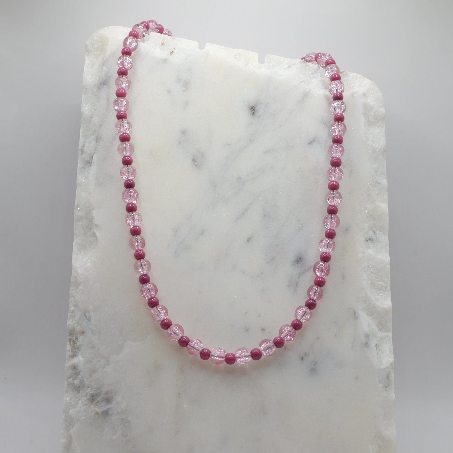 Necklace with pink beads on a marble surface