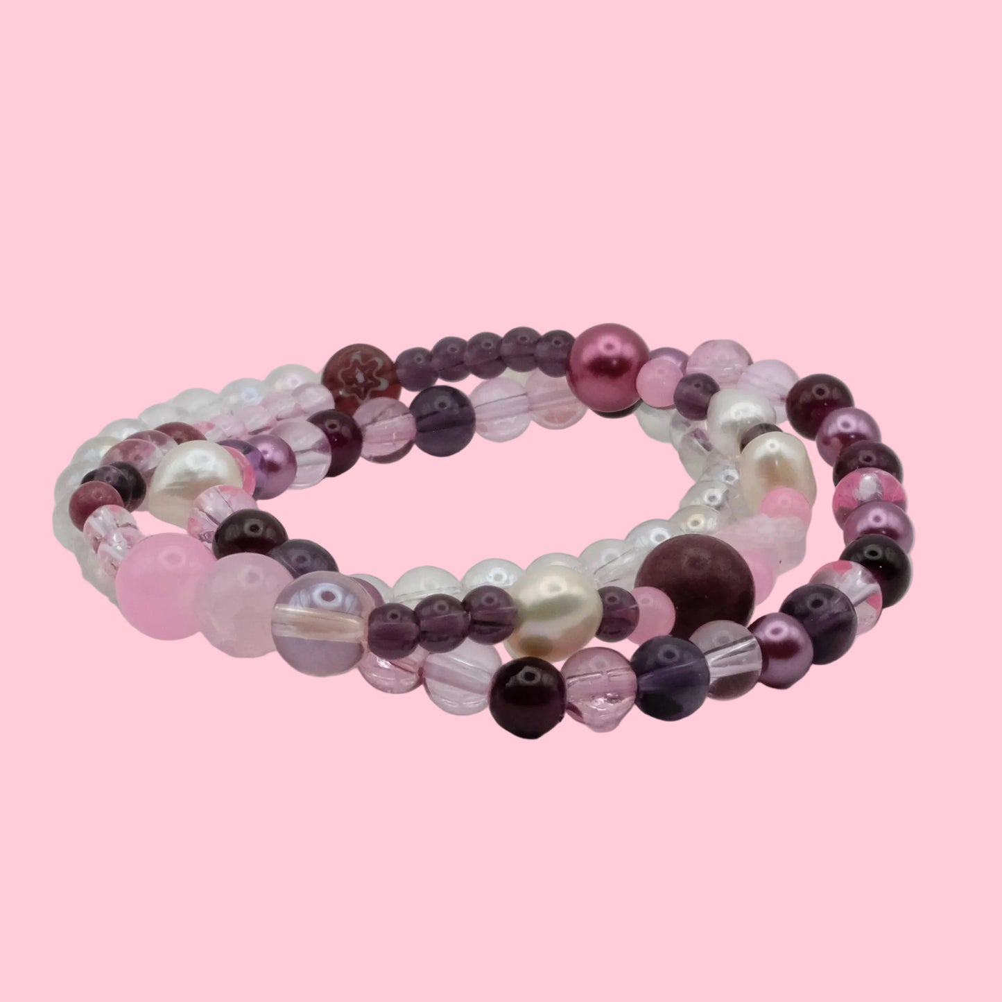 Layered handmade bracelet stack featuring pink and plum glass beads, freshwater pearls, pearl-look beads and crystal accents.