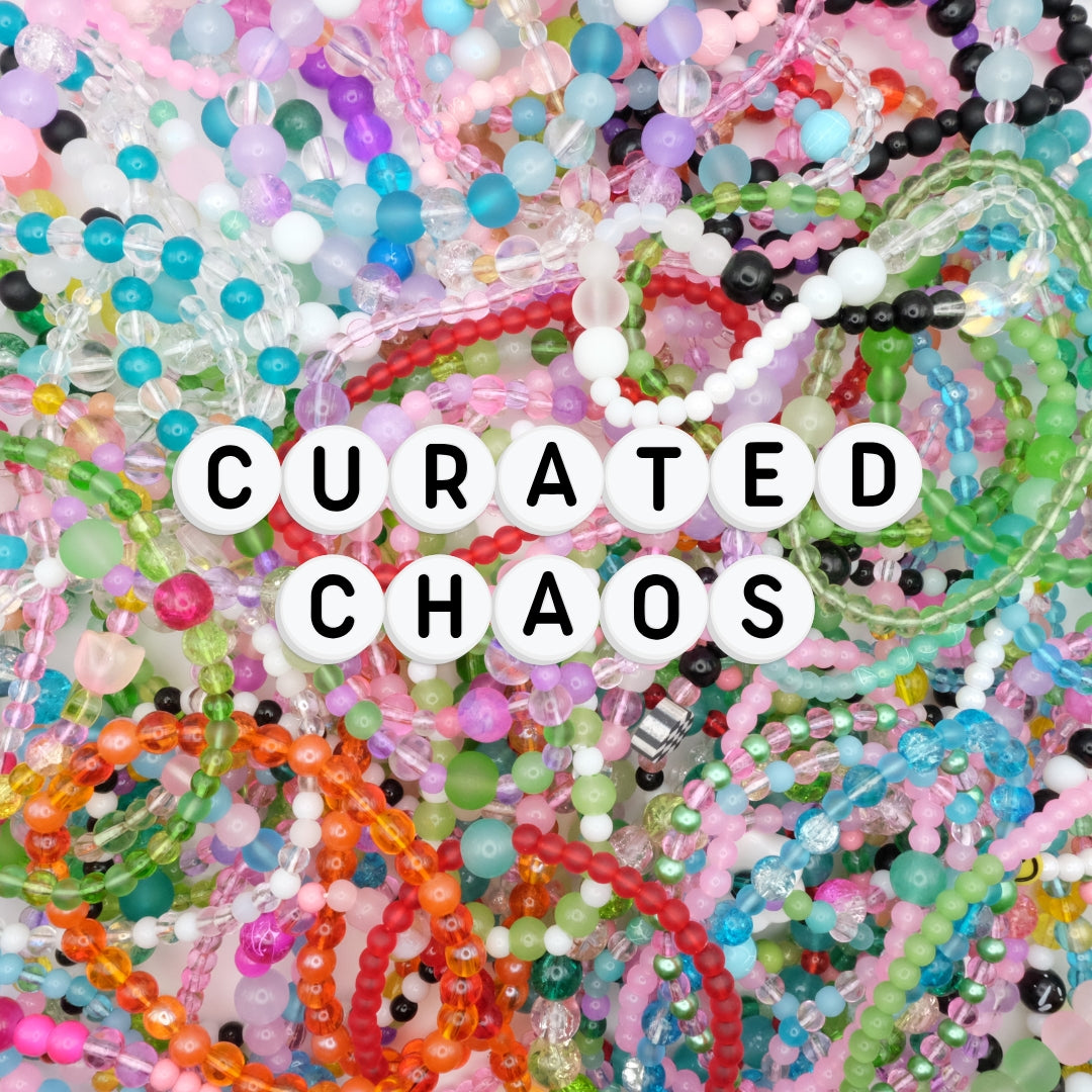 An array of colourful beaded bracelets in every colour of the rainbow. The words "Curate Chaos" spelled out on white with black writing alphabet beads