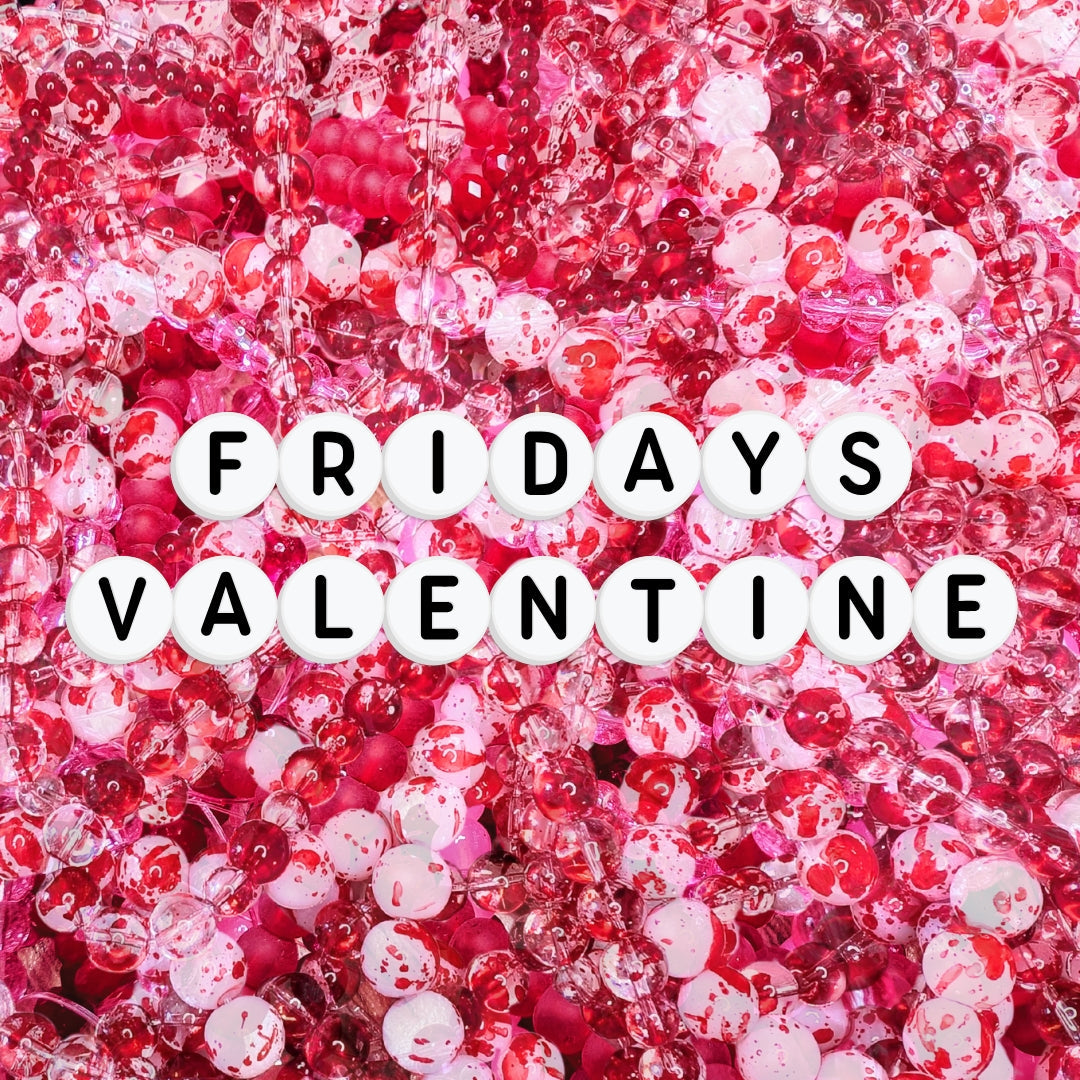 Flat lay of pink, red and clear glass beads with red splatter details, layered together with white letter beads spelling “FRIDAYS VALENTINE” across the centre.