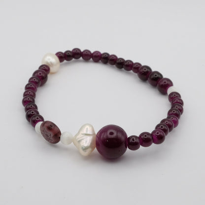 Beaded bracelet with purple and white beads on a light gray background