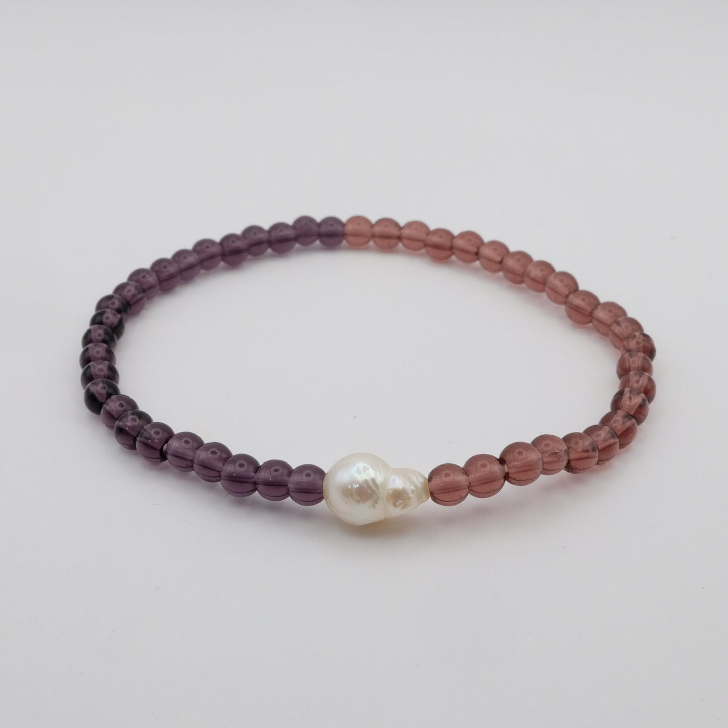 Beaded bracelet with a pearl on a light gray background
