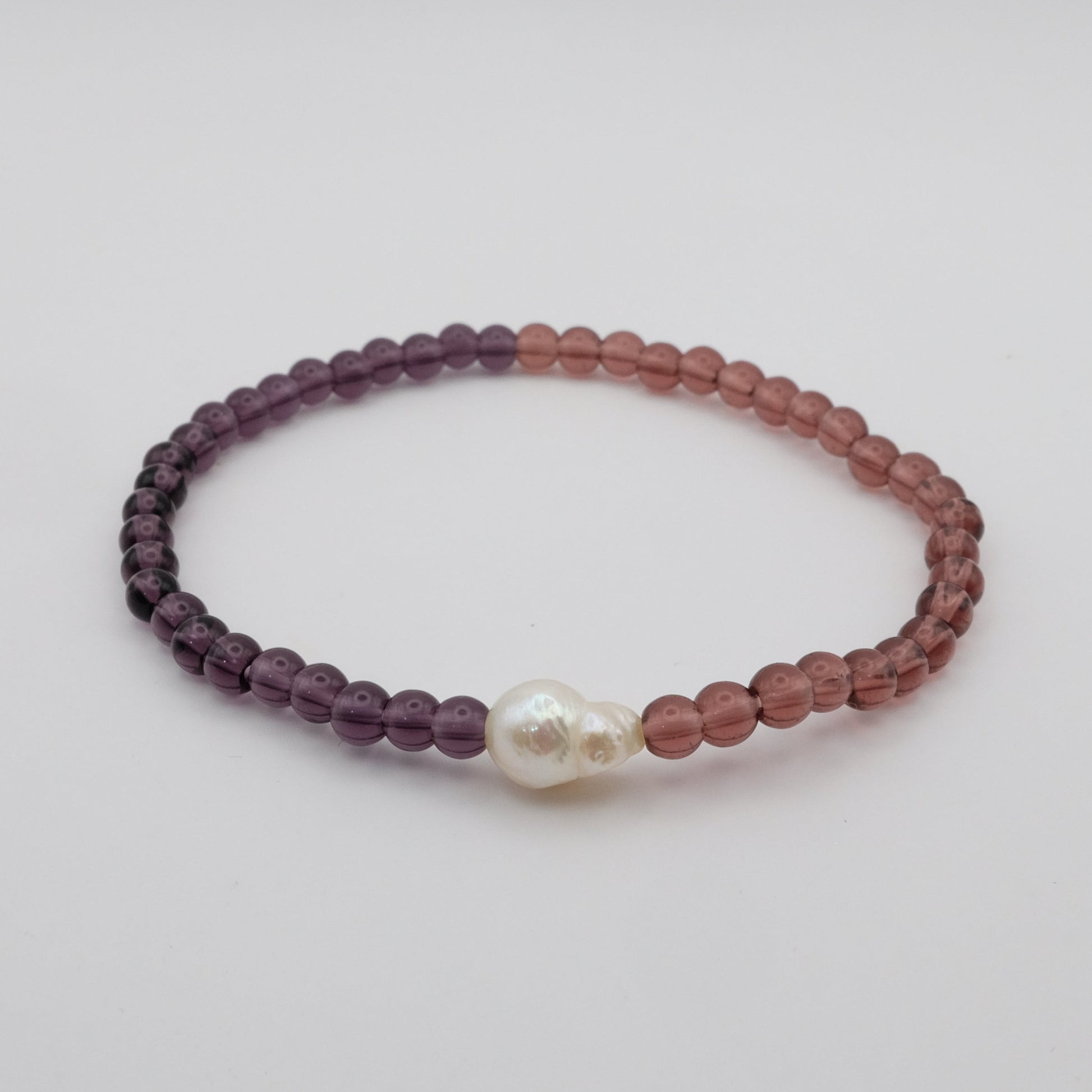 Beaded bracelet with a pearl on a light gray background