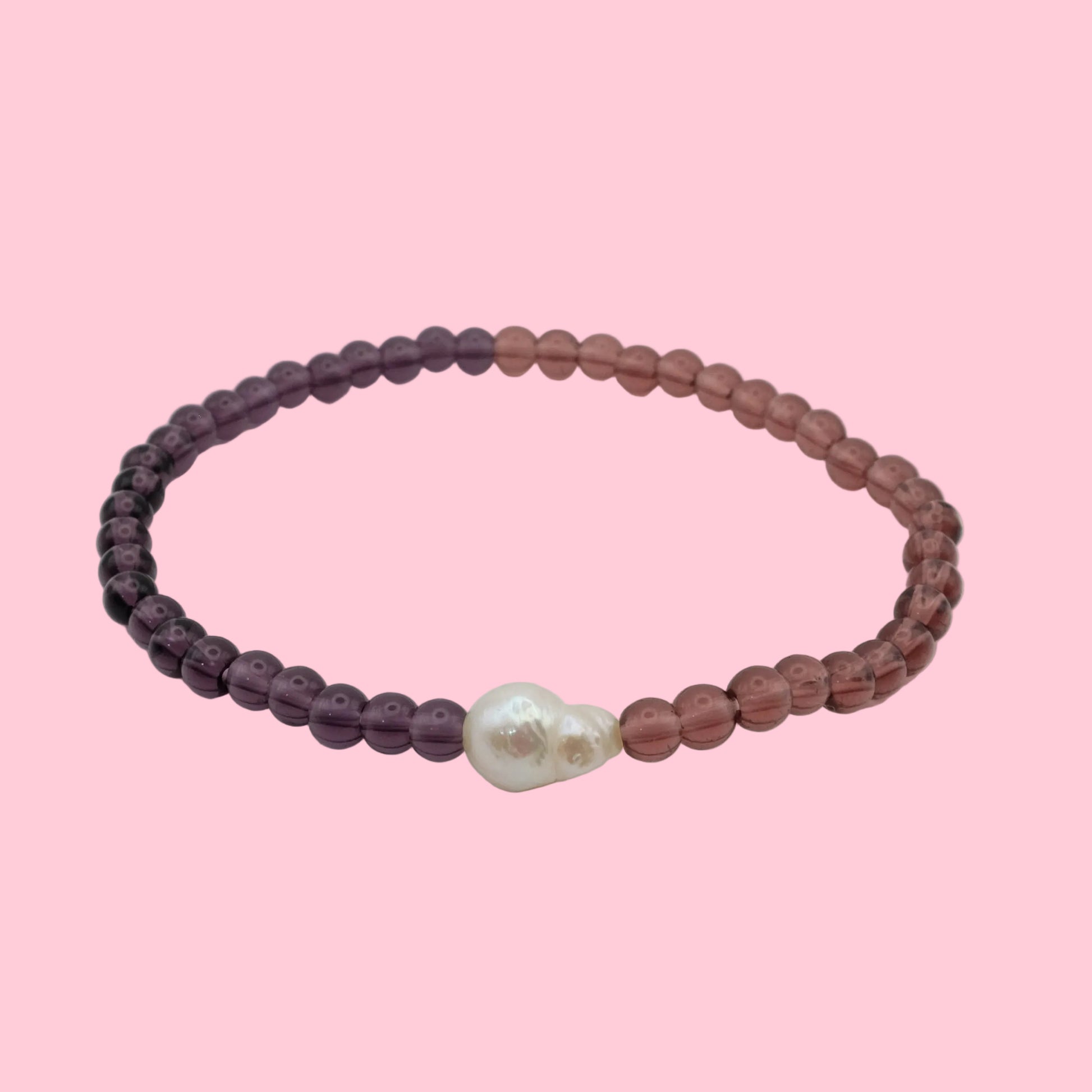 An elastic beaded bracelet composed of deep purple and light burgundy 4mm glass beads, featuring a single freshwater pearl at the centre, shown on a white background.