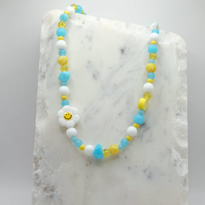 Beaded necklace with a smiley face charm on a marble surface