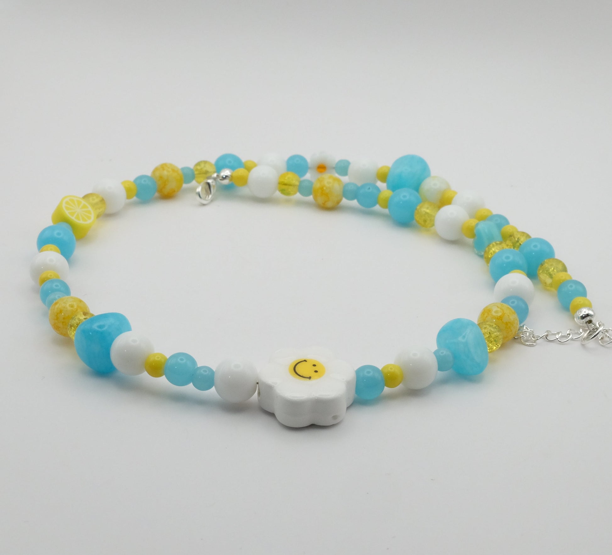 Colorful beaded necklace with white, yellow, and blue beads on a light gray background