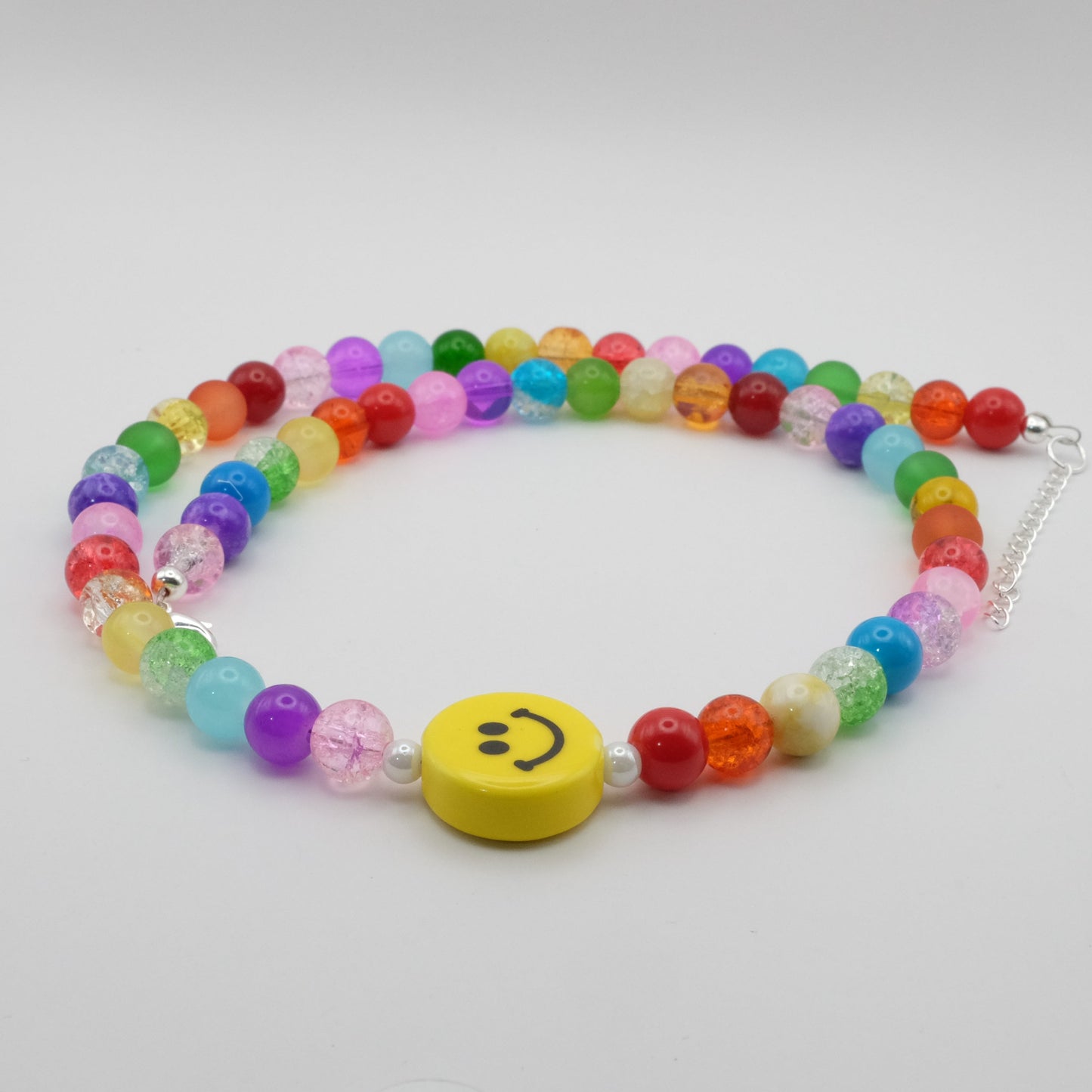 Colorful beaded necklace with a smiley face charm on a white background