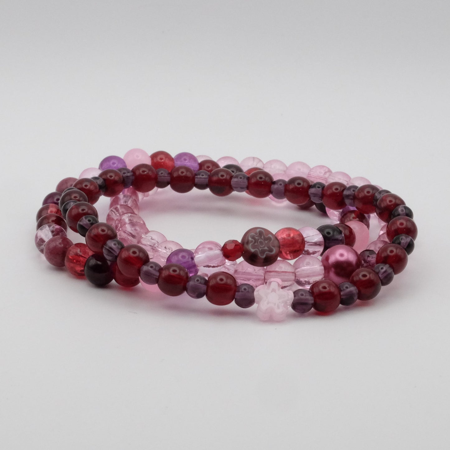 Set of beaded bracelets in red and pink on a light gray background