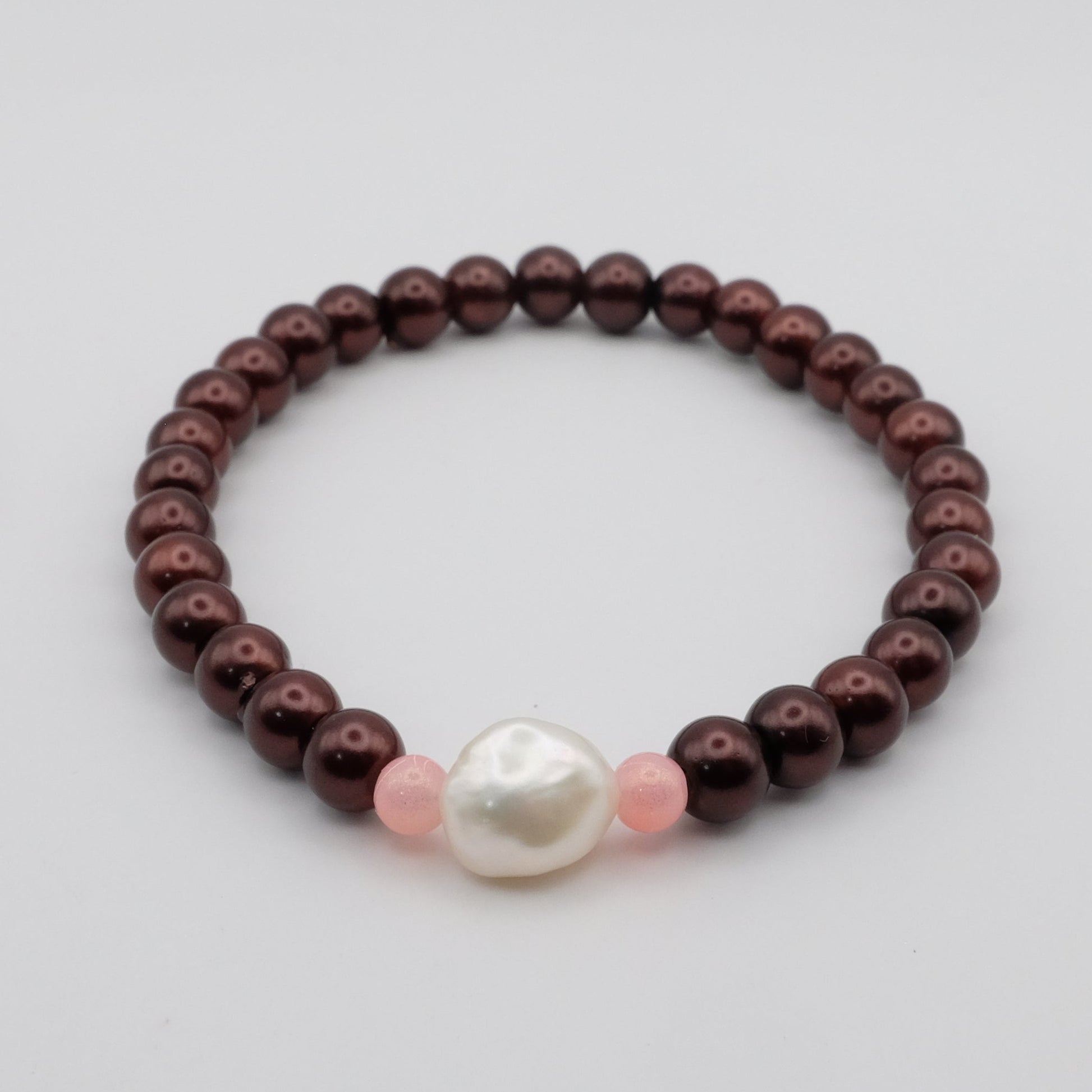 Bracelet with brown beads and a pearl on a light gray background