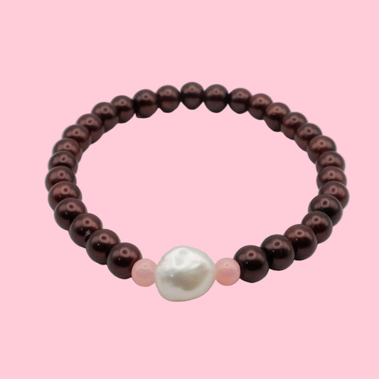 An elastic beaded bracelet composed of metallic burgundy pearl-finish 8mm glass beads featuring a freshwater pearl centrepiece with soft pink accent beads, shown on a white background.