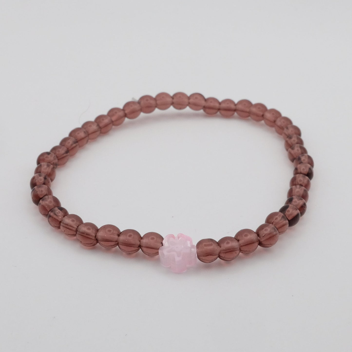 Beaded bracelet with a pink heart charm on a light gray background