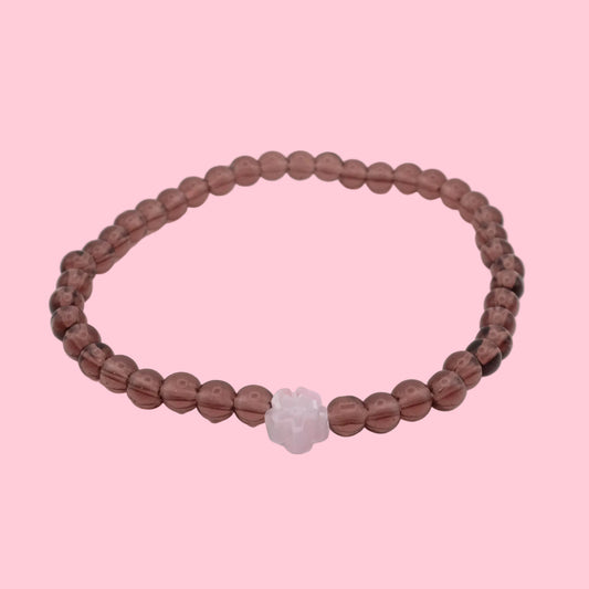 An elastic beaded bracelet composed of light burgundy 4mm glass beads, featuring a single translucent pink flower bead at the centre, shown on a white background.