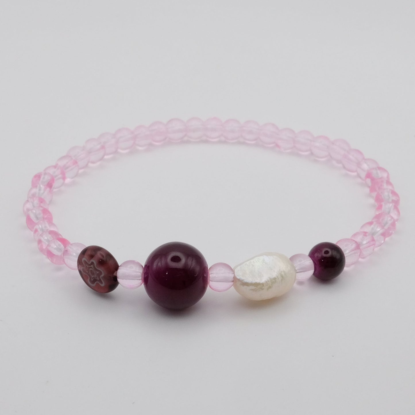 Bracelet with pink lace and three beads on a light gray background