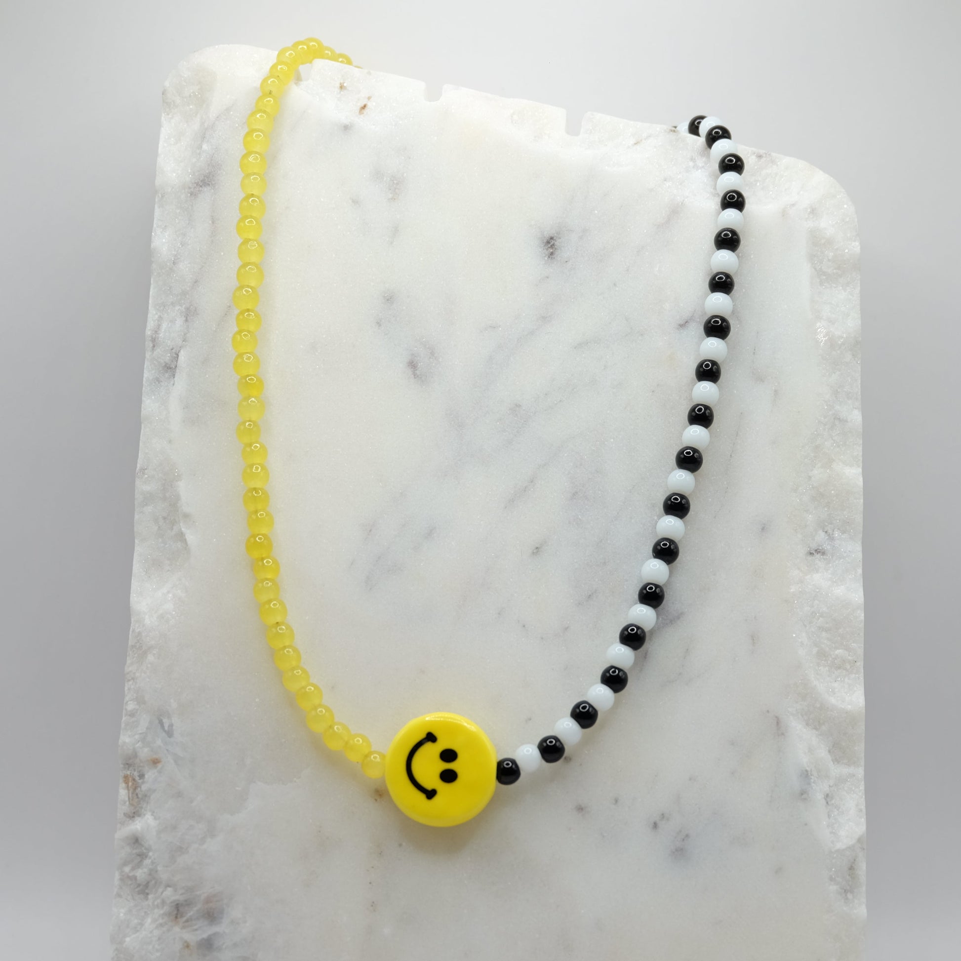 Necklace with smiley face charm on a marble surface