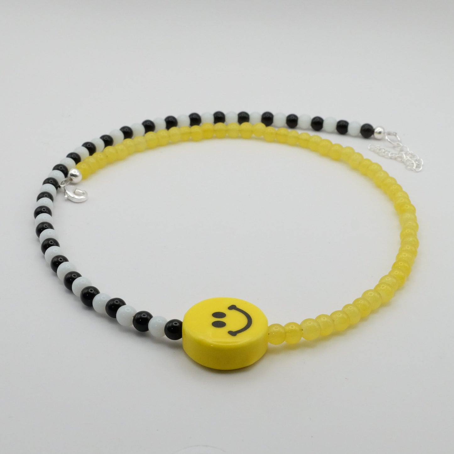 Necklace with yellow smiley face bead on a white background