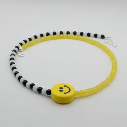 Necklace with yellow smiley face bead on a white background