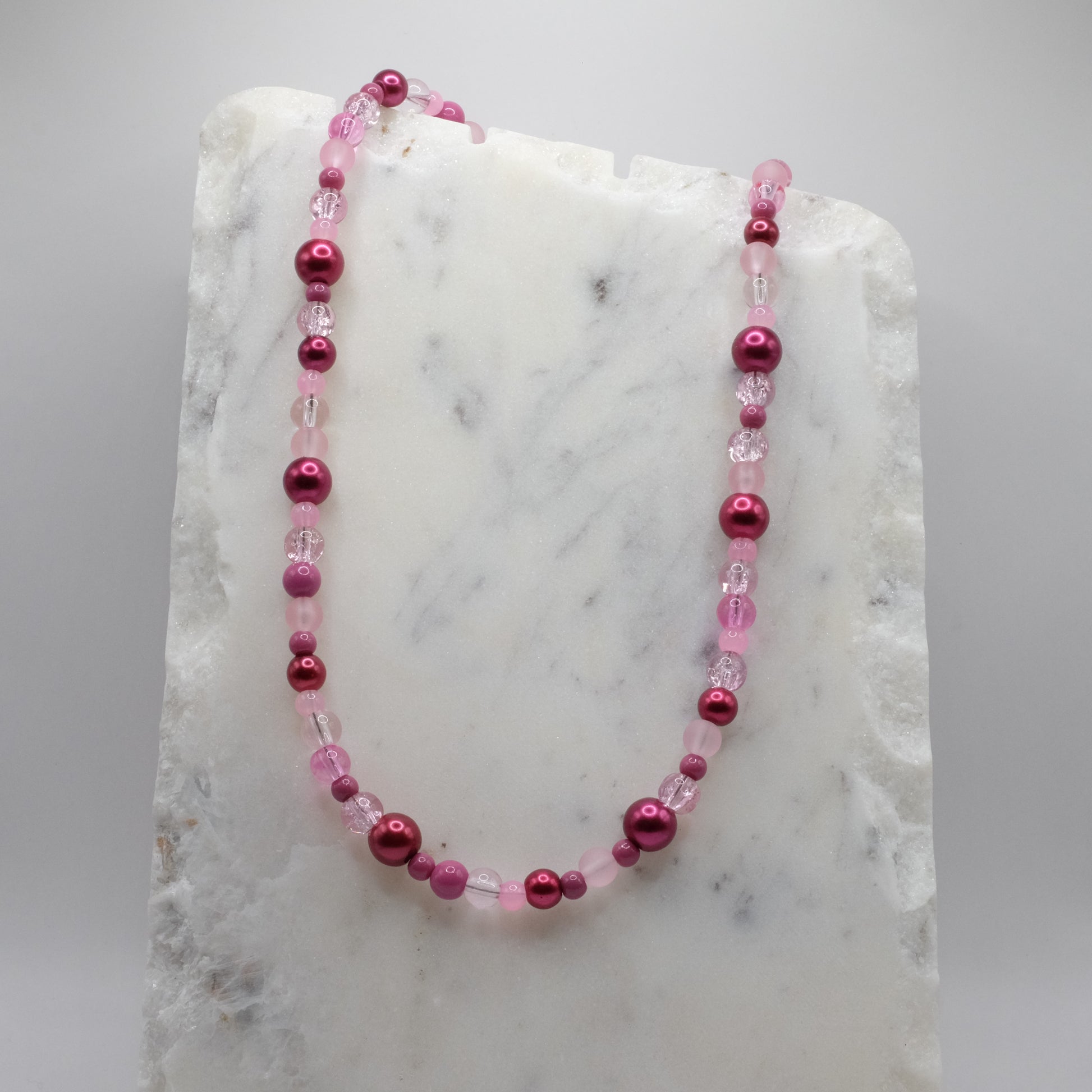 Pink beaded necklace on a marble surface