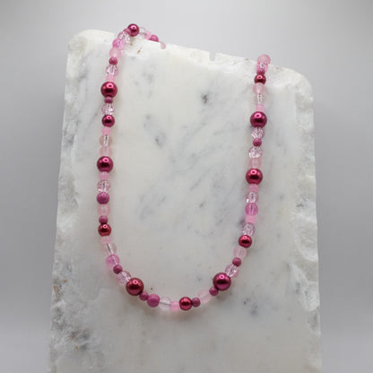 Pink beaded necklace on a marble surface