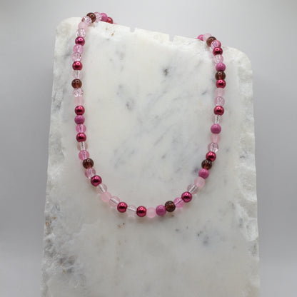Beaded necklace with pink and red beads on a marble surface