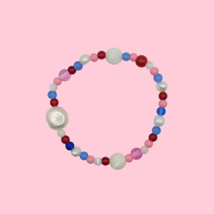An elastic beaded bracelet composed of 4mm and 6mm glass beads in pink, red and blue - featuring mother of pearl and freshwater pearls, shown on a neutral background.