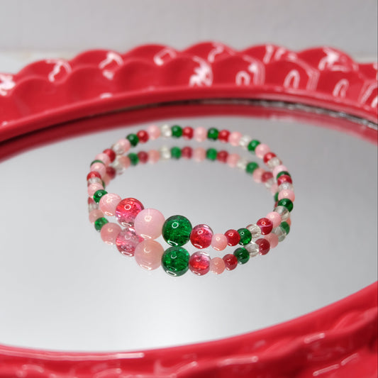 Beaded bracelet with red, green, and pink beads on a red mirror