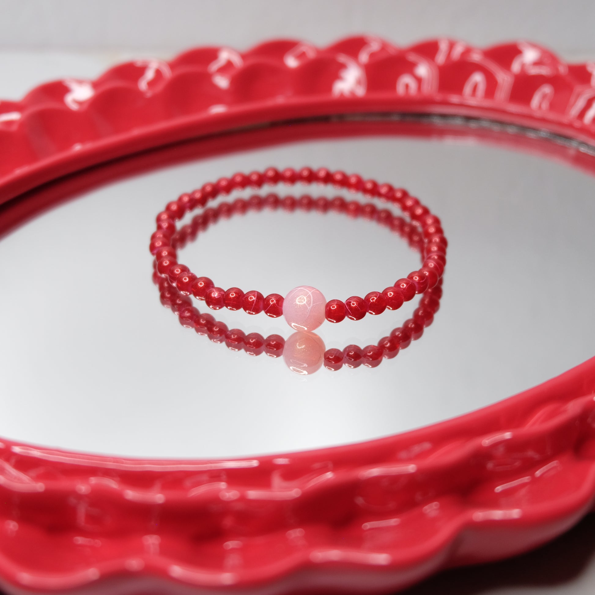 Red beaded bracelet on a red decorative plate
