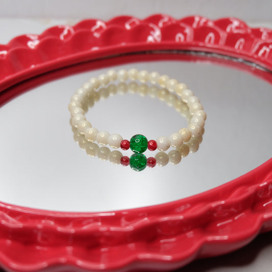 Pearl bracelet with red and green beads on a red decorative plate