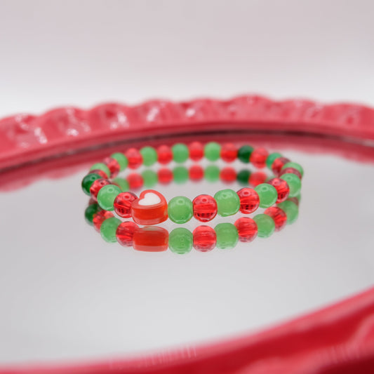 Red and green beaded bracelet on a clear glass surface with a red border.