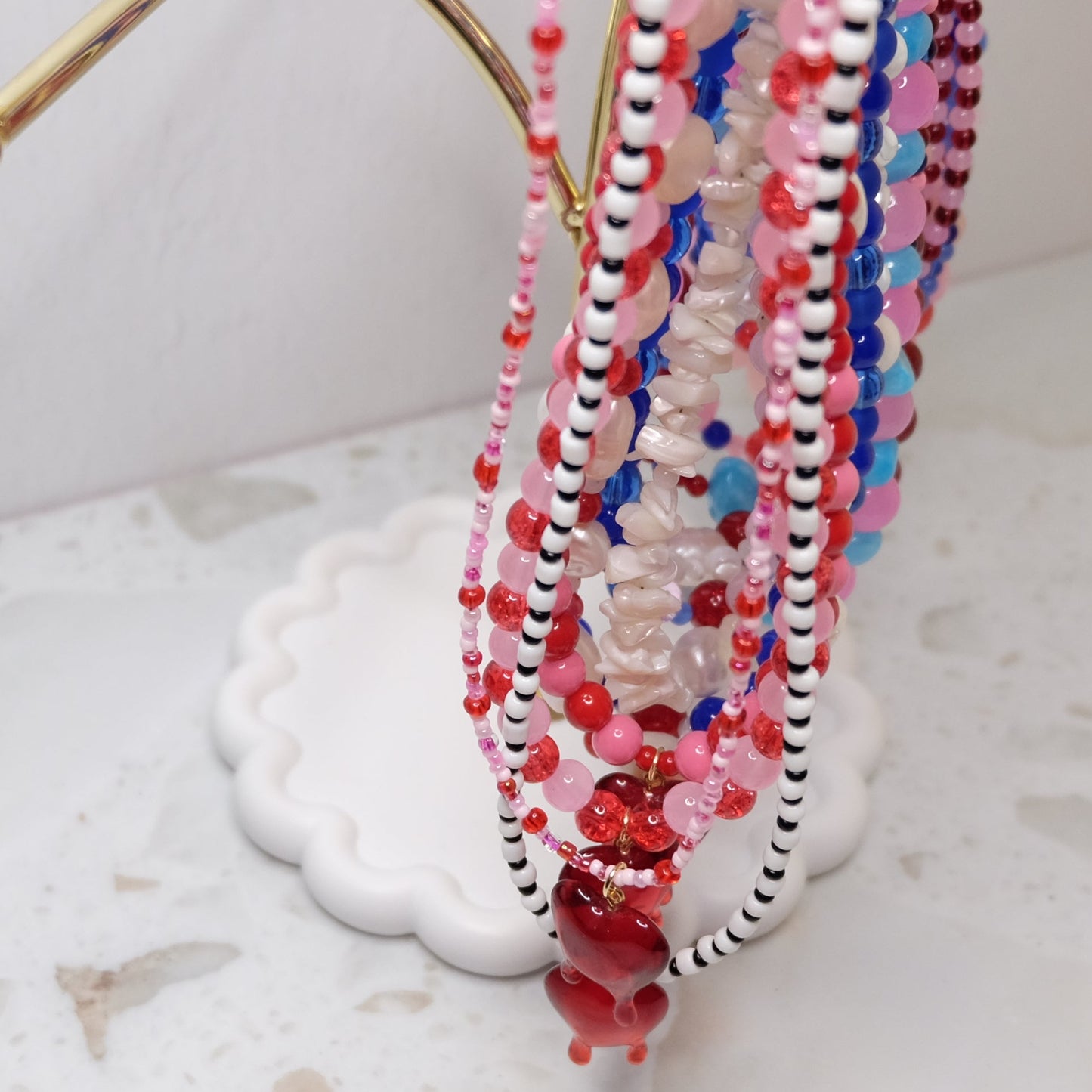 Colorful beaded necklaces on a white stand against a light background