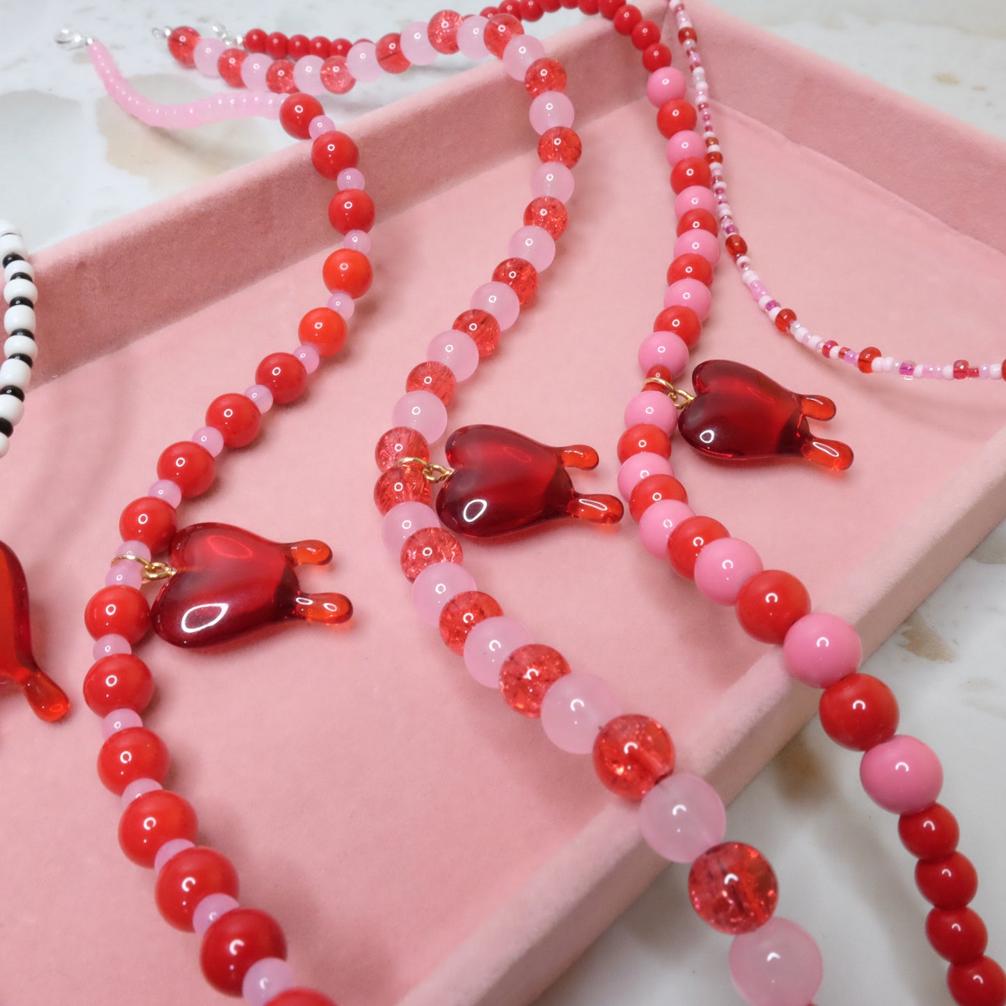 Necklace with red and pink heart-shaped beads on a pink surface