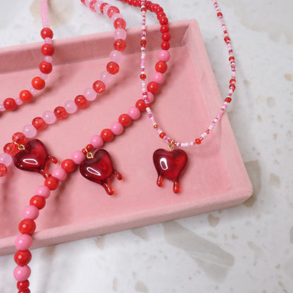 Pink and red necklace with red heart pendants on a pink tray