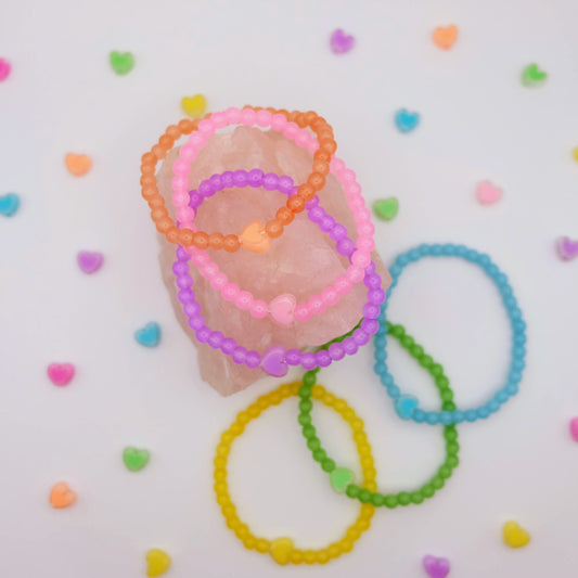 Colorful beaded bracelets on a white background with heart shapes