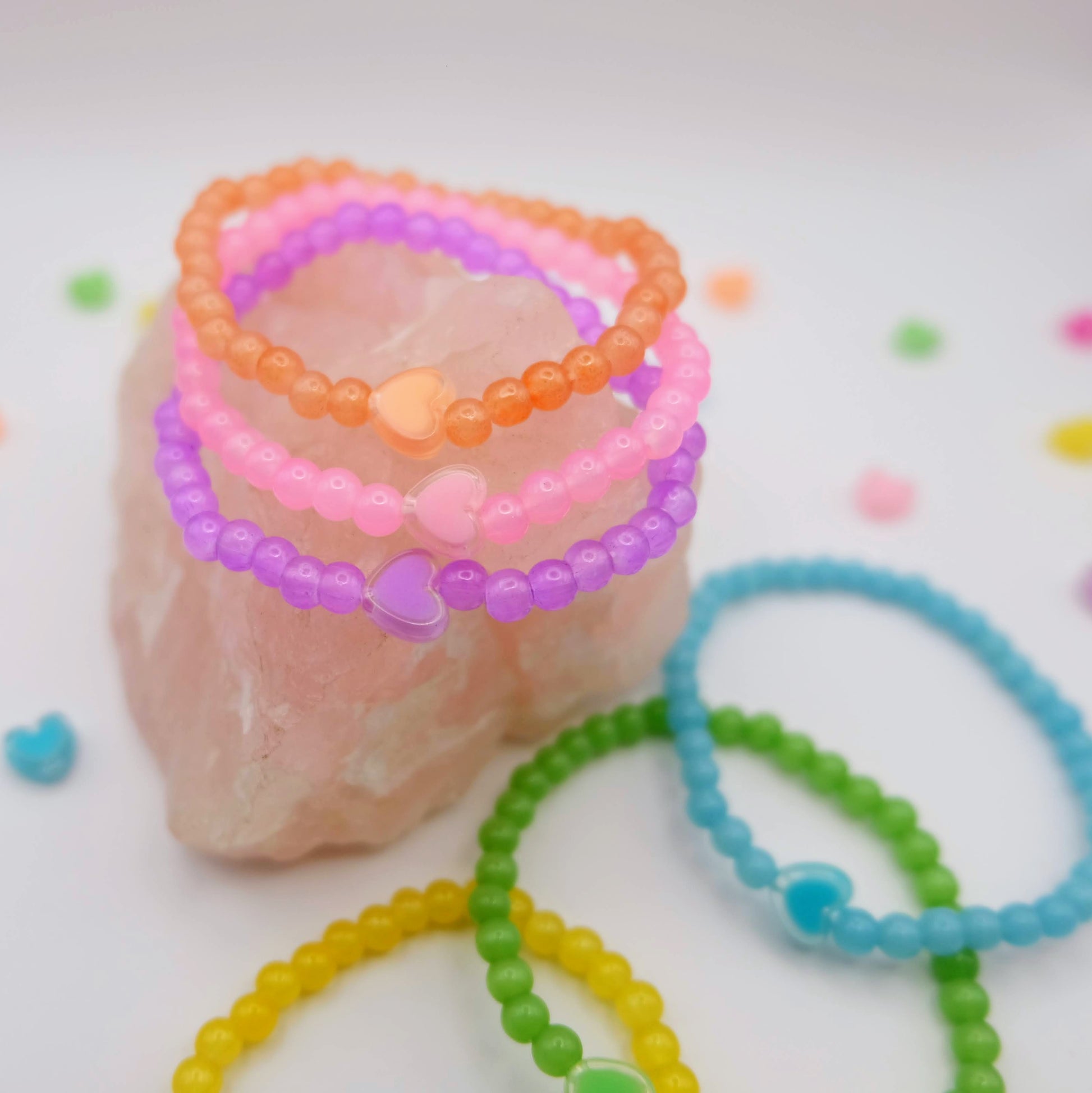 Colorful beaded bracelets on a pink stone with a white background